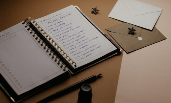A tidy desk setup featuring a planner, to-do list, envelopes, and a pen.