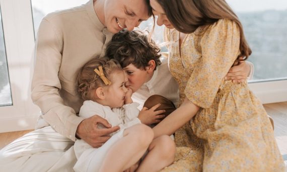 A happy family of four sitting together and sharing a loving moment indoors.